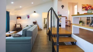 A modern living room with a sofa, a chair, a staircase, and a dining area. - Istra Green Soul Apartment (Oprtalj)