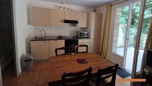 Una cocina compacta con armarios de madera, microondas y una mesa de comedor con sillas.