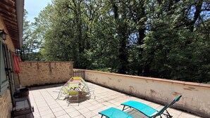 Un patio con mesa y sillas, piso de baldosas y pared de piedra.