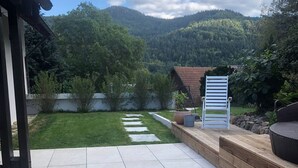Eine Terrasse mit Bergblick, eine Holzterrasse und ein Blumengarten.