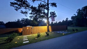 A modern outdoor structure with a wooden facade, a flag, and a well-lit pathway.