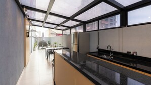 A modern kitchen with a black countertop, stainless steel appliances, and a glass ceiling. - Movi Life Torre 2 (São Paulo)