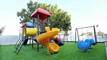 Un patio de juegos con tobogán, columpios y una estructura para escalar.