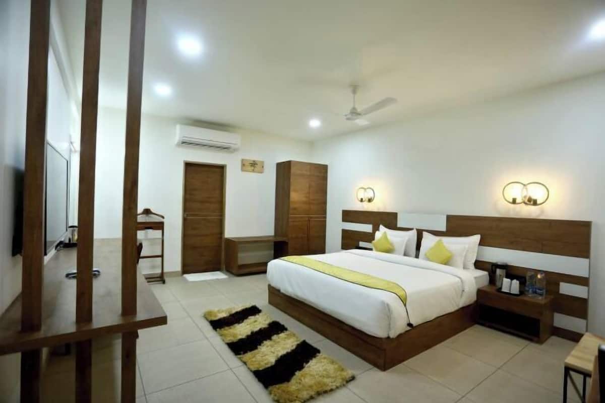 Une chambre à coucher comprenant un lit, des tables de chevet, une commode, une armoire en bois, un ventilateur de plafond et des lampes fixées au mur.