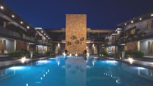 A swimming pool with a central stone wall and modern buildings on either side. - Phoenix Resort (Rajkot)