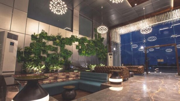 A modern lobby with a green wall, seating area, and decorative lighting. - Phoenix Resort (Rajkot)