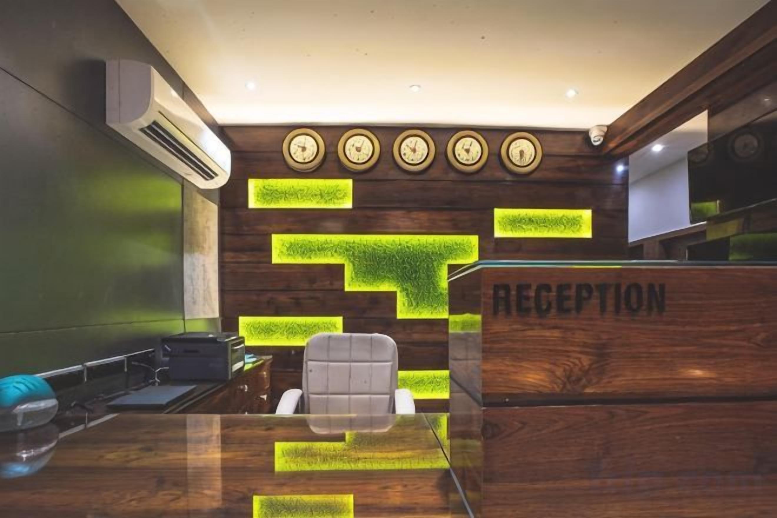 A reception desk with a wooden finish and a 'RECEPTION' sign, a modern air conditioning unit, and a seating area with a glass table.