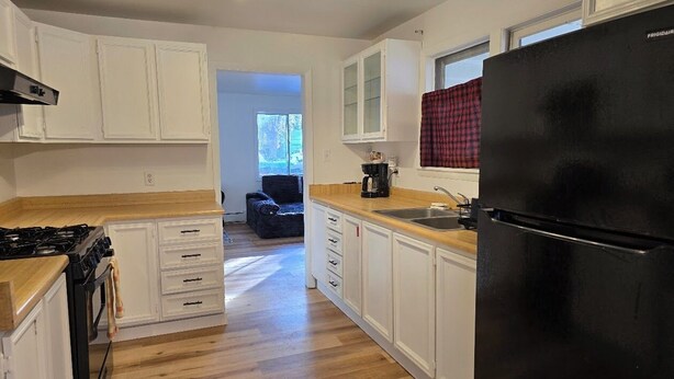 A kitchen with white cabinets, a black refrigerator, and a wooden countertop. - Welcome to your getaway destination in Craig's rugged outdoors loving terrain. (Craig)