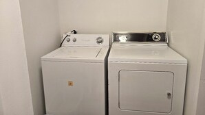 A laundry room with two white washing machines and a metal shelf above them. - Welcome to your getaway destination in Craig's rugged outdoors loving terrain. (Craig)