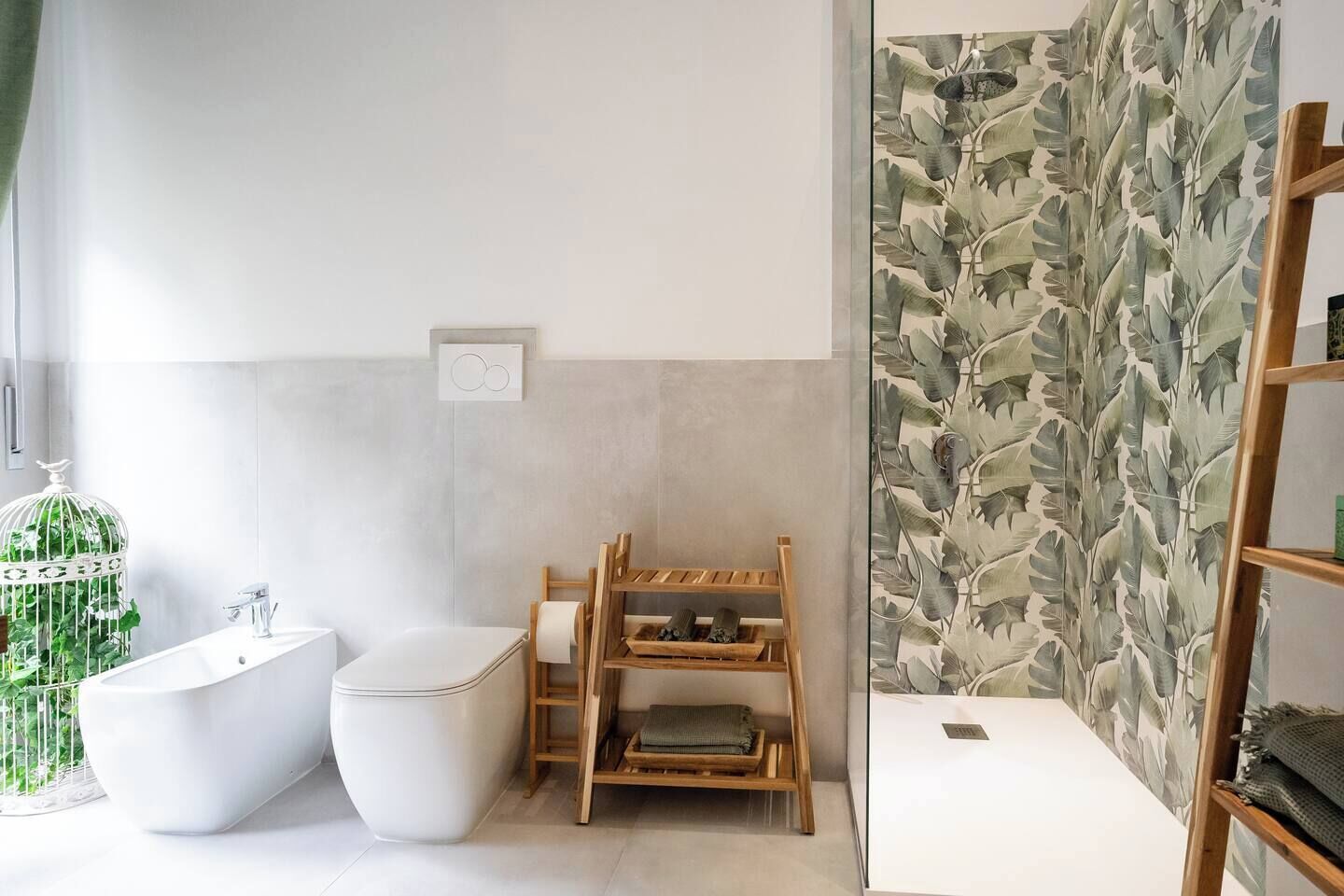 Un baño moderno con una bañera independiente, un inodoro y un tendedero de madera.