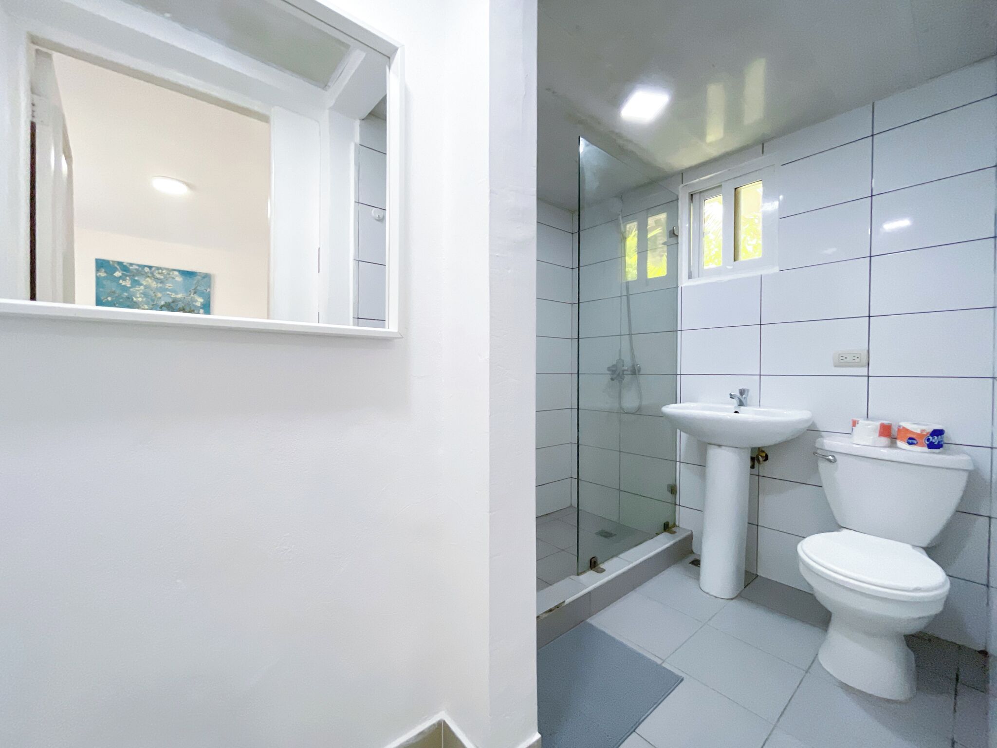 A modern bathroom with a white sink, toilet, and glass shower enclosure.