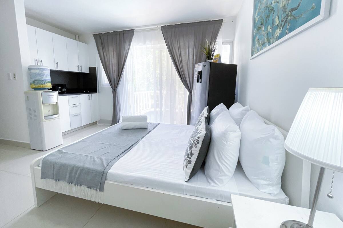 Ein modernes Hotelzimmer mit Bett, Schreibtisch, Wasserspender und Fernseher.