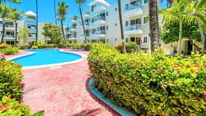 A resort with a central swimming pool, surrounded by lush greenery and palm trees. - GO TO THE BEACH STAYS (Punta Cana)