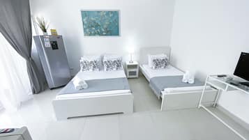 A modern hotel room with two beds, a desk, a TV, and a painting on the wall.