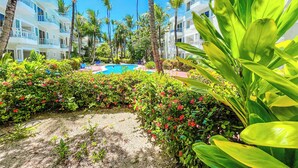A resort with a swimming pool surrounded by lush greenery and palm trees. - GO TO THE BEACH STAYS (Punta Cana)
