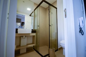 A modern bathroom with a glass shower enclosure, a white sink, and a toilet. - On Brooklin (São Paulo)