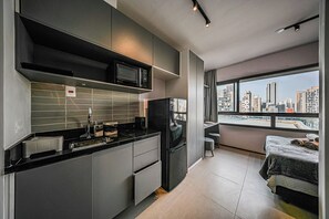 A modern kitchen with a microwave, refrigerator, and a view of a cityscape through a large window. - On Brooklin (São Paulo)