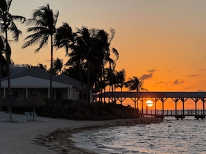 A beachside resort with a pier, palm trees, and a sunset. - Couples Retreat on Exclusive Sunset Key (Key West)