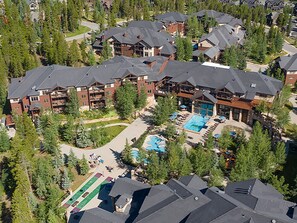 Luchtbeeld van een resort met meerdere gebouwen, een zwembad en een tennisbaan.