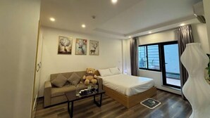 Ein modernes Hotelzimmer mit Bett, Sofa, Couchtisch und einem Kunstwerk an der Wand.