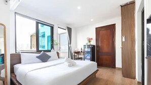 Hotellihuone, jossa on sänky, työpöytä, tuoli, vaatekaappi ja suuri ikkuna.