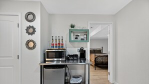 Een kleine keuken met een magnetron, koffiezetapparaat en een koffiecorner.