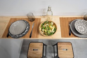 Ein Holztisch mit verzierten Tellern, einer Salatschüssel, einer Flasche und Besteck.