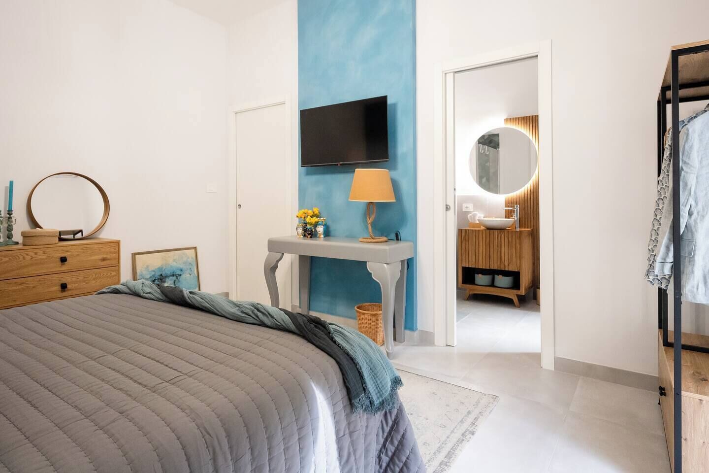 Una camera da letto con un letto, una cassettiera, un comodino, una lampada e un televisore.