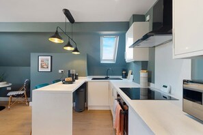 A modern kitchen with a central island, pendant lighting, a window, and a built-in oven.