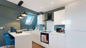 A modern kitchen with a central island, white cabinetry, a built-in oven, and a window above the sink.