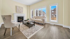 Una sala de estar con chimenea, un sofá color beige, un sillón acolchado y una mesa de centro.