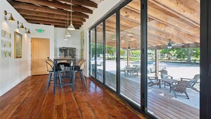 A spacious indoor area with a wooden ceiling, large windows, and a view of the outdoor patio. - Ensign Loft 8 at Farragut Lofts (Bay Saint Louis)