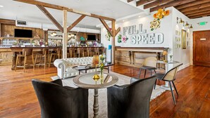 A spacious bar area with wooden beams, a white sofa, and a round table with chairs. - Ensign Loft 8 at Farragut Lofts (Bay Saint Louis)
