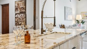 A kitchen with a marble countertop, a vintage-style faucet, and two wine glasses. - Ensign Loft 8 at Farragut Lofts (Bay Saint Louis)