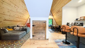 Un ambiente accogliente con soffitto in legno, un divano, un'area da pranzo e una cucina.