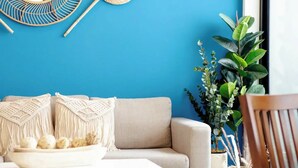 A modern living room with a blue accent wall, a beige sofa, and decorative wall art. - Catorce Urbano (San José)