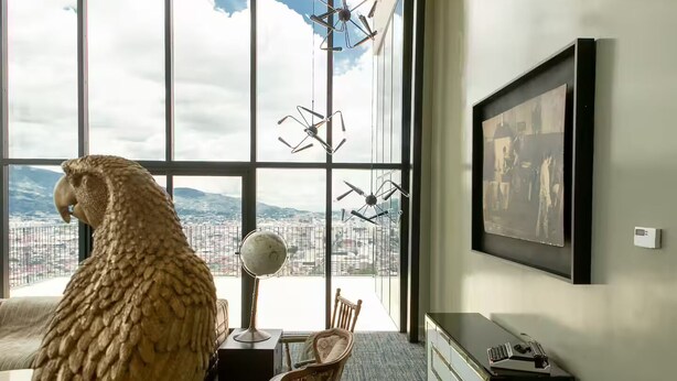 A room with a large window, a globe, a chair, and a framed picture on the wall. - Catorce Urbano (San José)