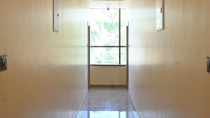 Um corredor com chão ladrilhado, iluminação embutida e uma janela no final.