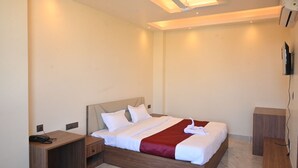 A hotel room with a bed, bedside tables, a TV, and a ceiling fan.