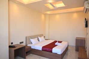 A hotel room with a bed, bedside tables, a TV, and a ceiling fan.