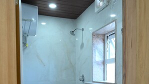 A small, compact bathroom with a shower, toilet, and sink.