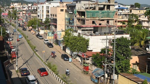 A busy urban street with buildings, vehicles, and a clear sky.