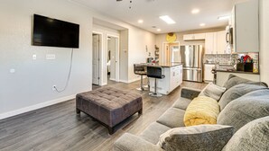 A modern living room with a large grey sectional sofa, a dark brown ottoman, and a ceiling fan.