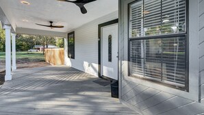 A covered porch with a ceiling fan, a door with a window, and a view of a backyard.