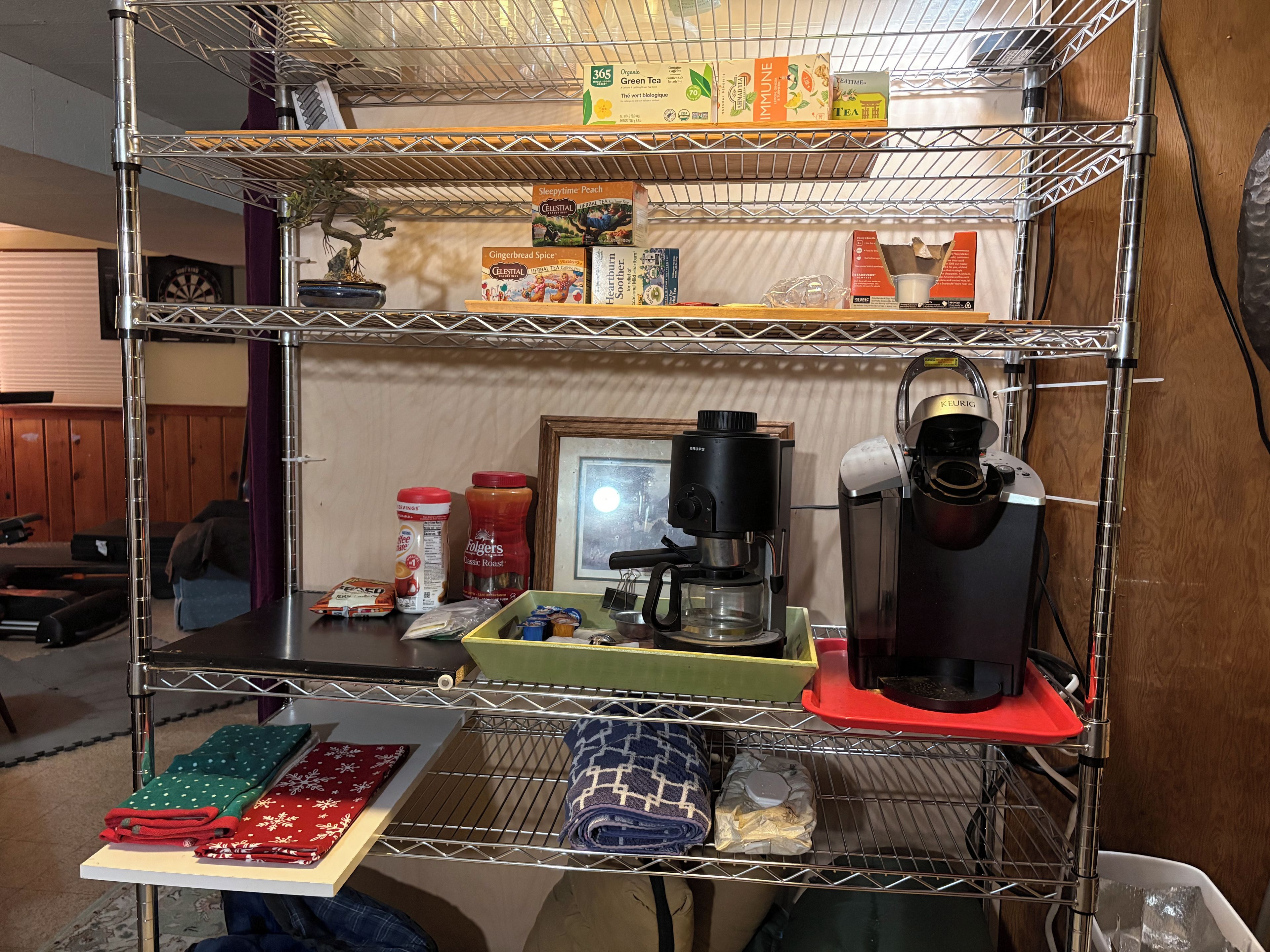Una cocina equipada con cafetera, estantes con cajas de té y un hervidor.