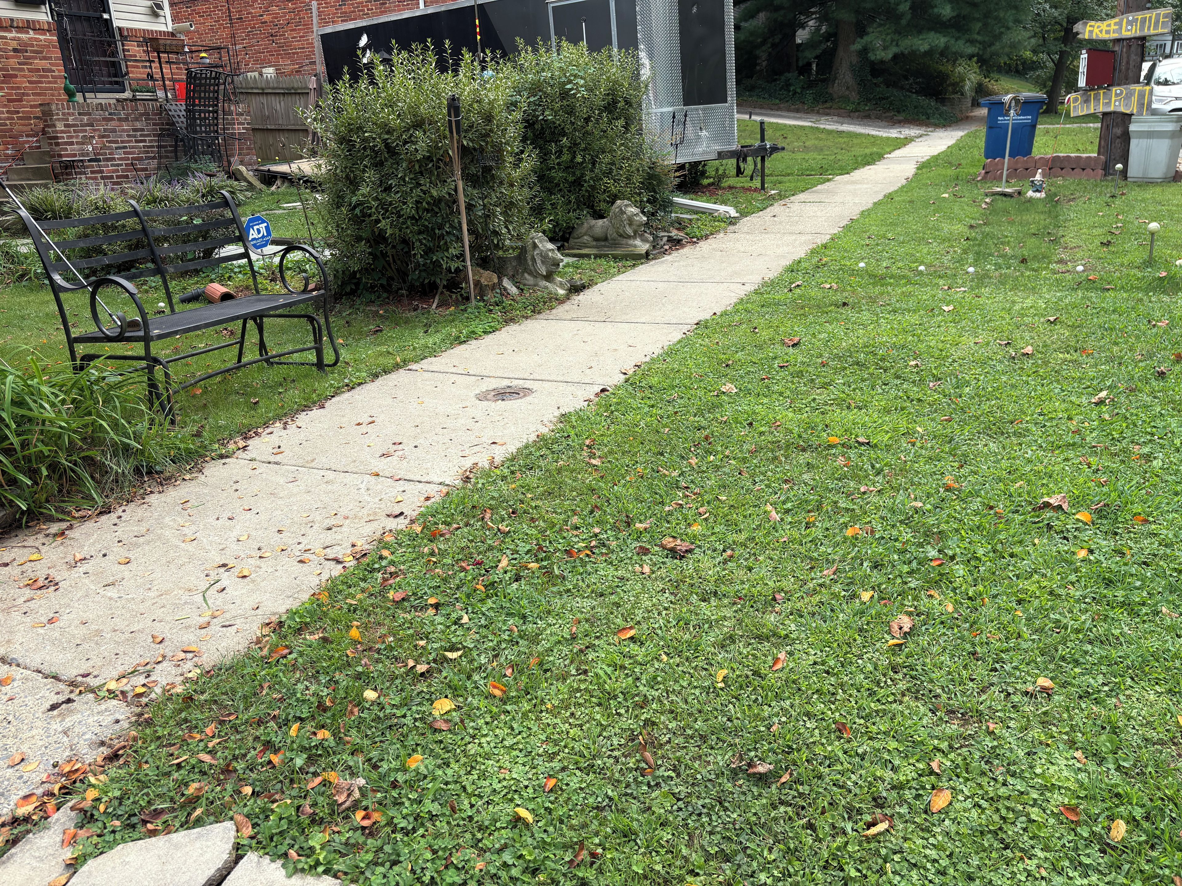 A pathway leading to a building with a brick facade, a bench, and a metal fence.