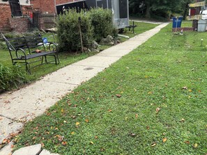 A pathway leading to a building with a brick facade, a bench, and a metal fence.
