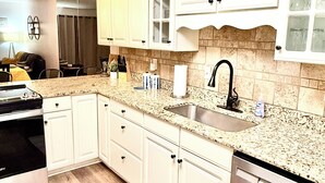 A modern kitchen with white cabinets, a granite countertop, stainless steel appliances, and a tiled backsplash. - Indoor Pool-Central Branson (Branson)