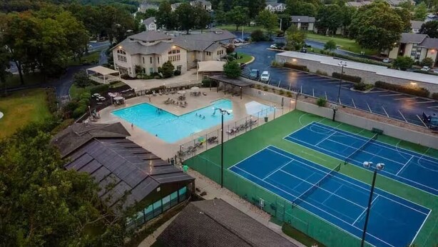 A residential area with a swimming pool, tennis courts, and a large house. - Indoor Pool-Central Branson (Branson)