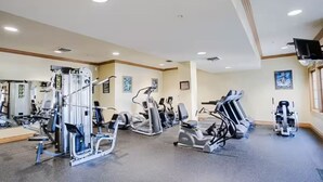 A gym with various exercise machines, mirrors, and a television on the wall. - Indoor Pool-Central Branson (Branson)